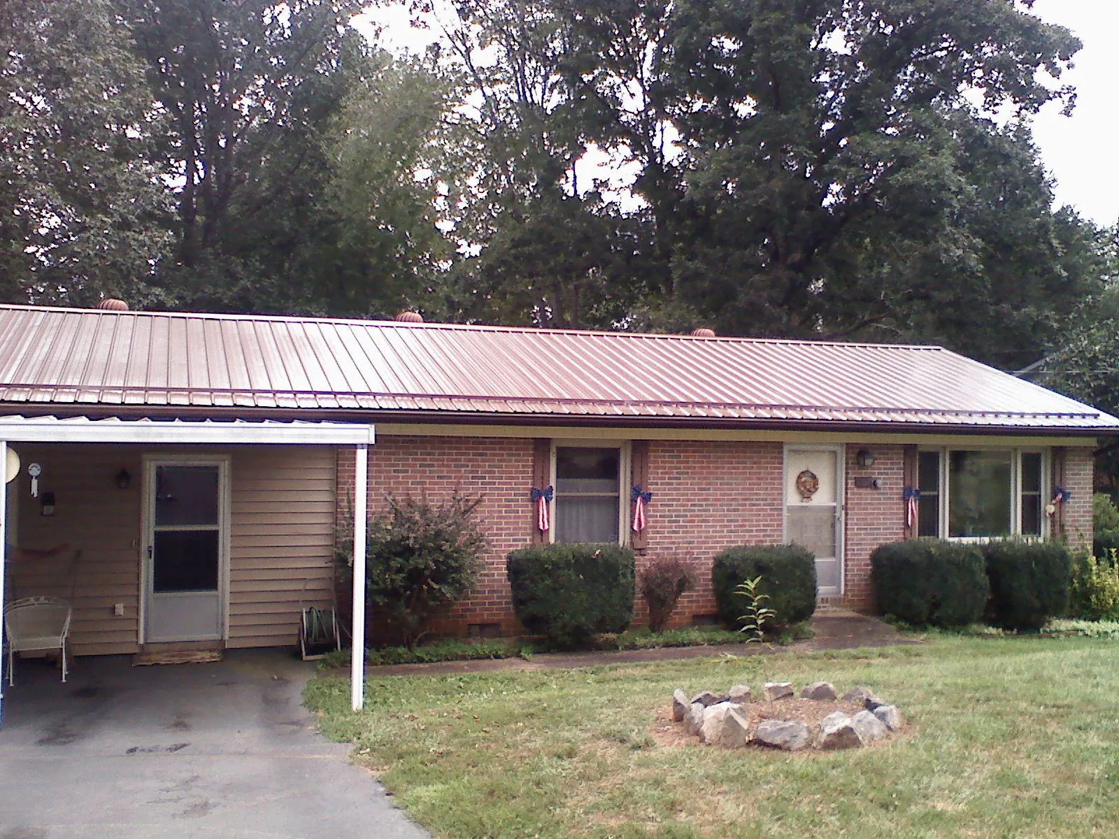 Bronze metal roof and carport on a brick ranch home — Roof Repair work by our crew in Woodward