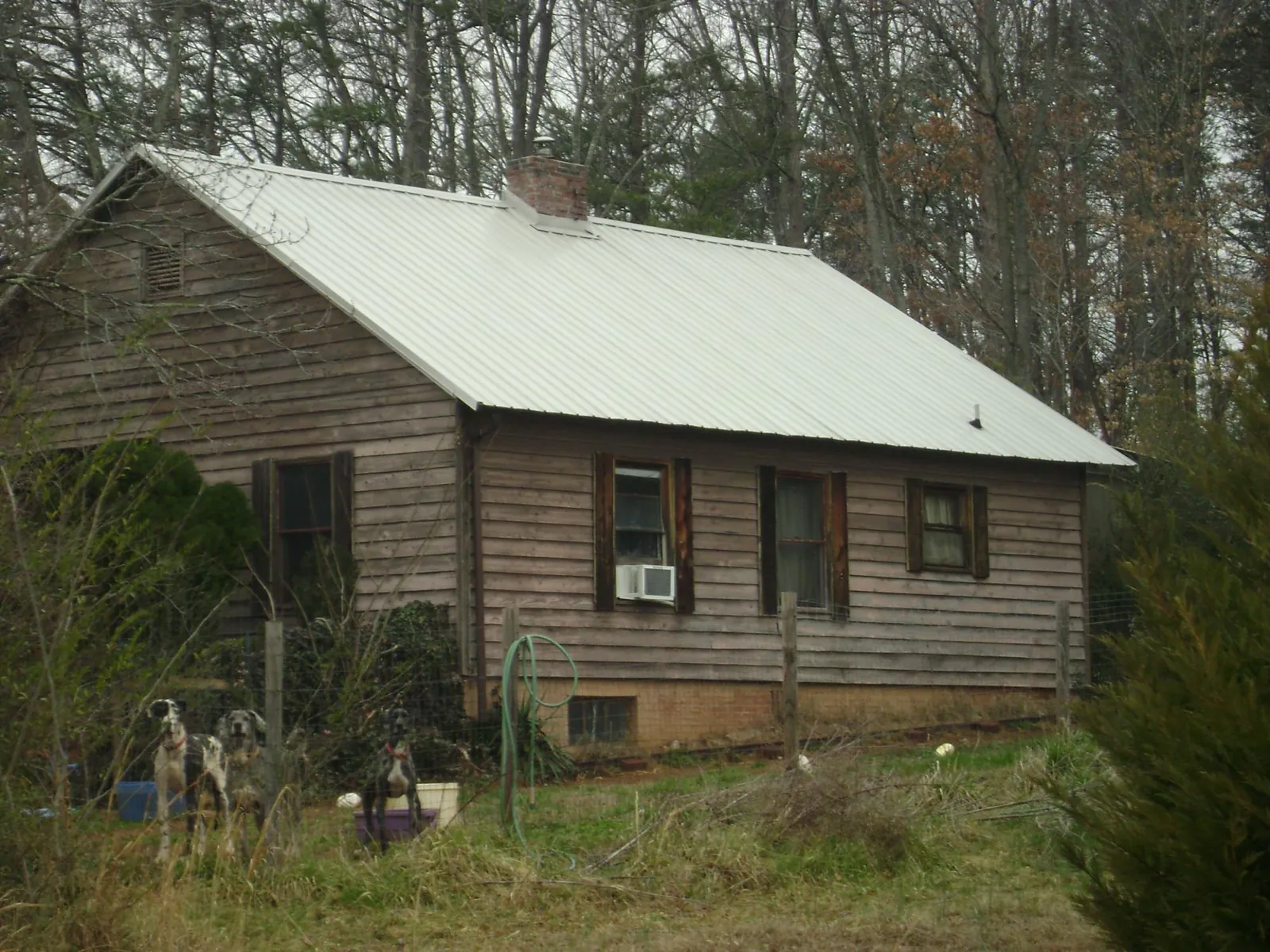 White metal roof on an old wood sided farmhouse, from a Metal Roof Installation job in Woodward