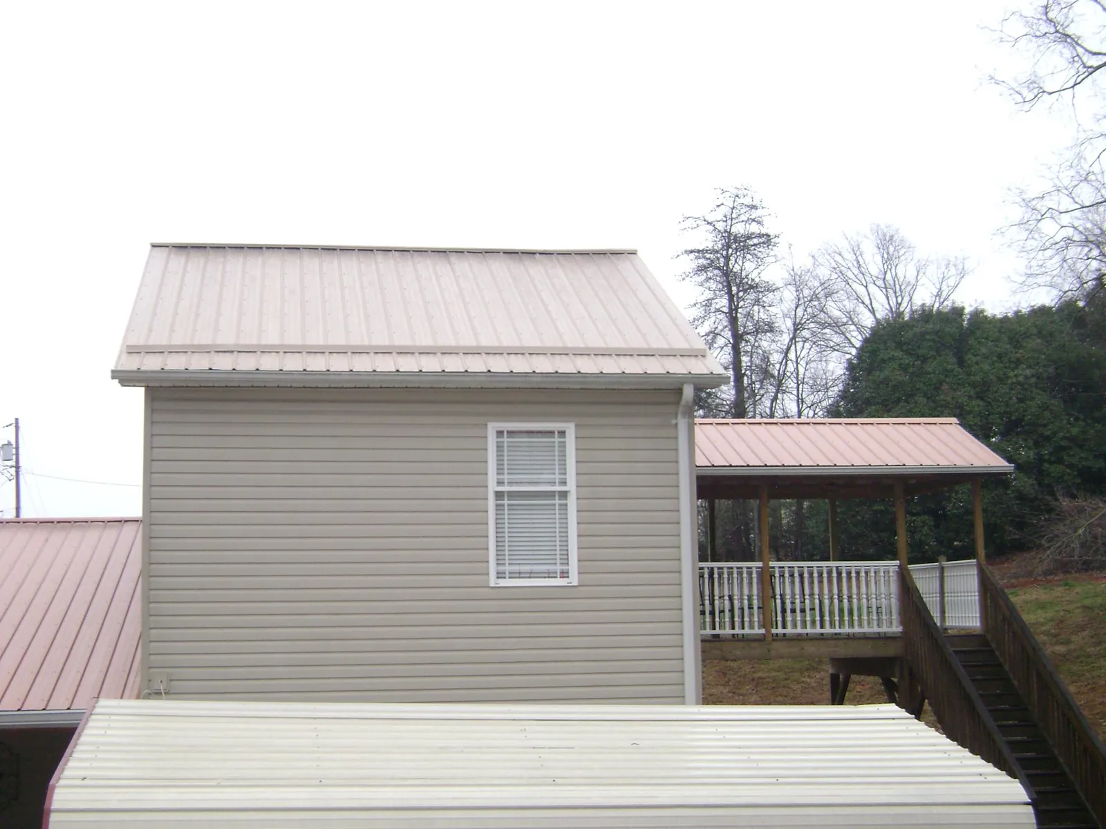 Tan metal roofs on a two story addition and attached porch, from a Roof Replacement job in Woodward